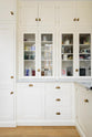 A closer view of the white shaker kitchen with glazed cupboards, drawers, and a Carrara marble countertop.