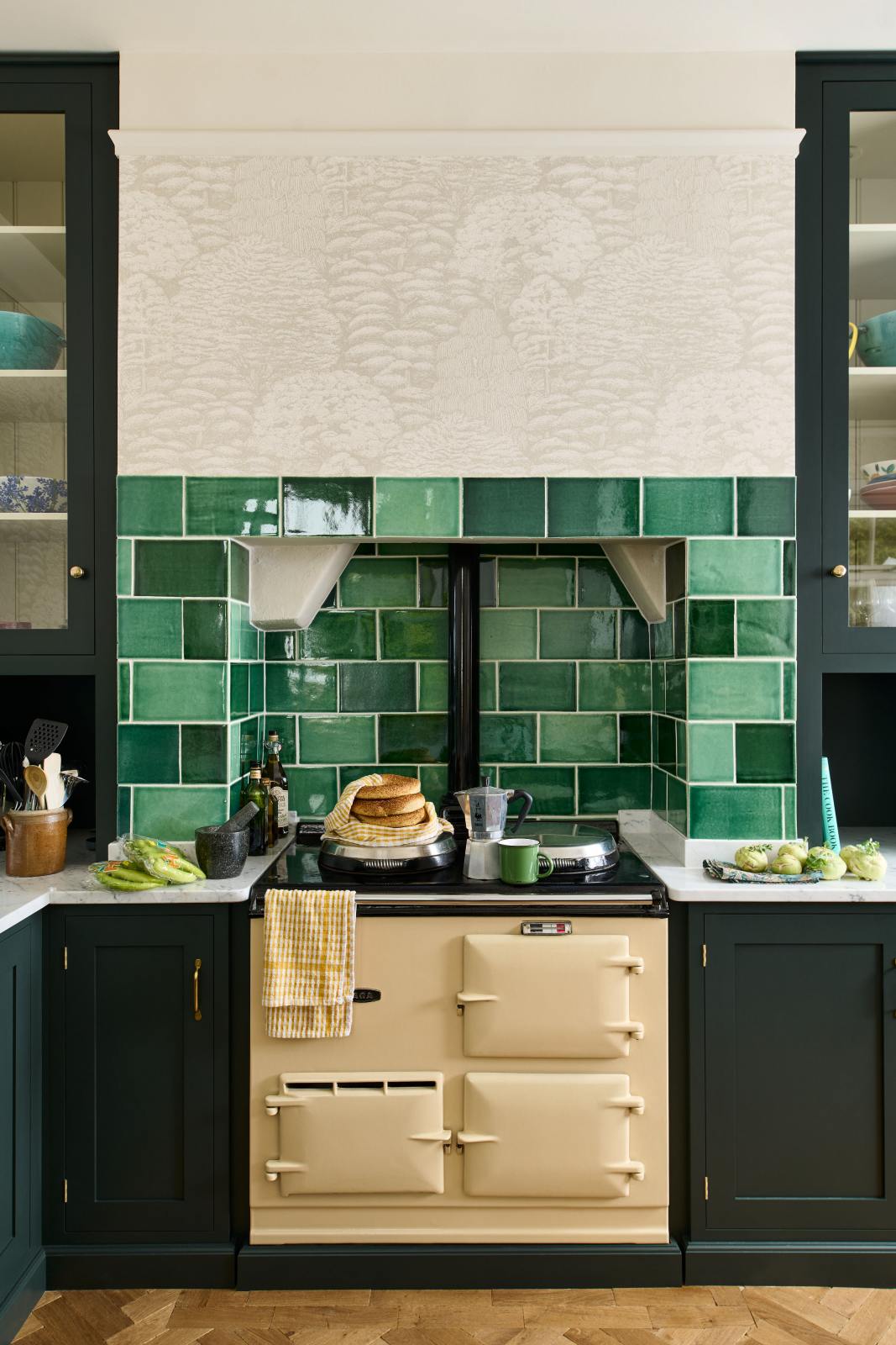 A closer look at the cream gas stove in the Bakehouse Green shaker kitchen’s sink run, featuring Carrara marble worktop. At the nook are the Emerald Green London tiles, which add colour to the off-white, delicately patterned wallpaper.