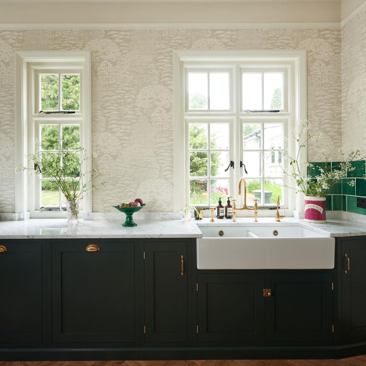 A closer look at the double Belfast sink with an aged brass Ionian tap in the Bakehouse Green shaker kitchen’s sink run, featuring Carrara marble worktop. At the nook are the Emerald Green London tiles, which add colour to the off-white, delicately patterned wallpaper.