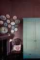 In the far corner of this wine-coloured room, an original Georgian fireplace is paired with a dark, glossy Windsor chair, deVOL’s Grand Tour Reading Lamp, and a collection of vintage Willow pattern plates displayed above the mantlepiece. To the right, a grand freestanding Classic English pantry painted in Clerkenwell blue completes the scene.
