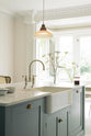 A closer look at the double Belfast sink in the Trinity Blue kitchen island with a Carrara marble worktop. Natural light from the original French doors brightens the simple kitchen.