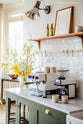 The custom off-white pantry showcases shelves and a marble countertop, adorned with a collection of beautifully minimalistic glazed ceramics, books, wooden utensils, a wooden chopping board, and a maroon bowl filled with lemons.