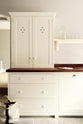 A minimalist white linen shaker kitchen featuring a dark polished sapele wood worktop with a countertop cupboard and an L-shaped sink run.