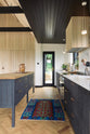 Nestled between a large and minimal Sebastian Cox kitchen, which features a long sink and cooker run with a Carrara marble worktop and a large kitchen island with a solid oak worktop, is a built-in bank of cupboards and a slim glass door leading to the gorgeous countryside of Tuscany. Beautifully decorated with artisan ceramics and a bright patterned rug, this kitchen creates a simple and practical space.