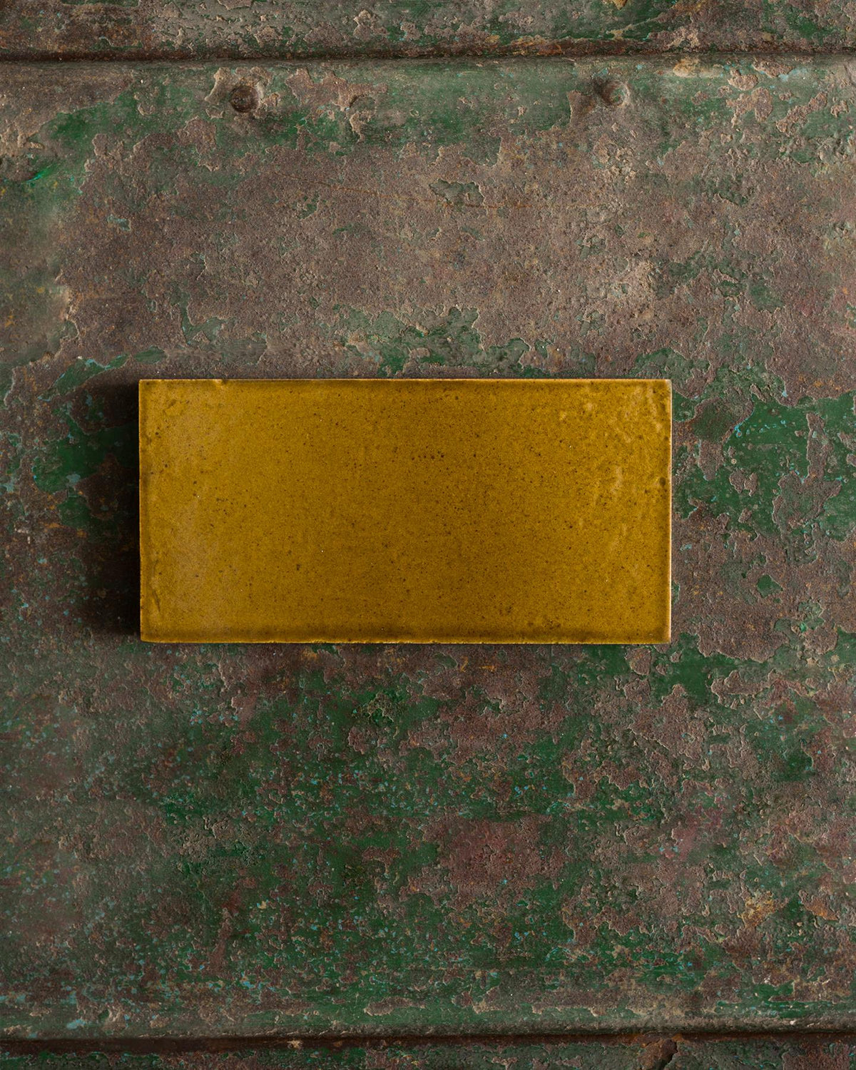 A glossy sepia metro tile on a rustic metallic surface. | Plain Metro TEST