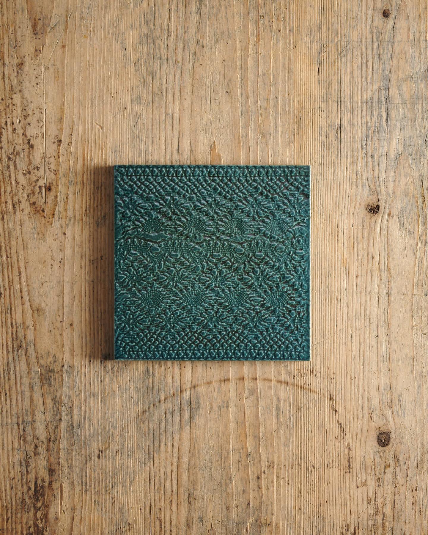 Teal textured square on a wooden surface.