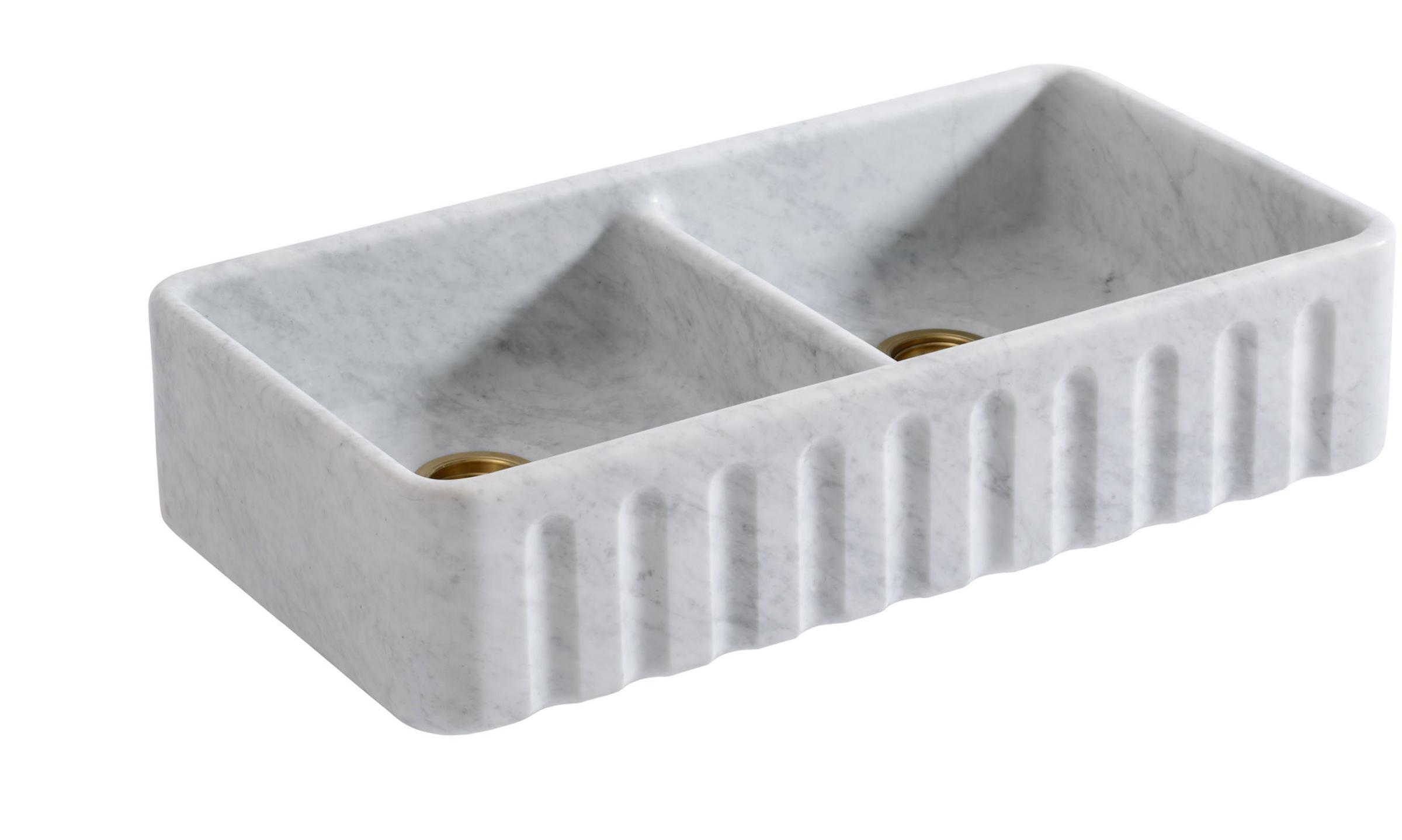 A cut-out image of a honed marble sink with subtle veining, a delicate fluted front and two basins.