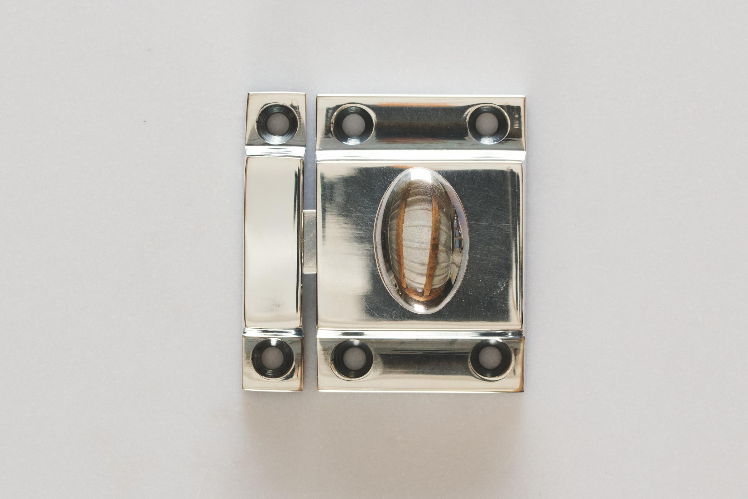 A square cupboard catch with an oval-shaped knob in a tarnished 'Bella' silver finish.