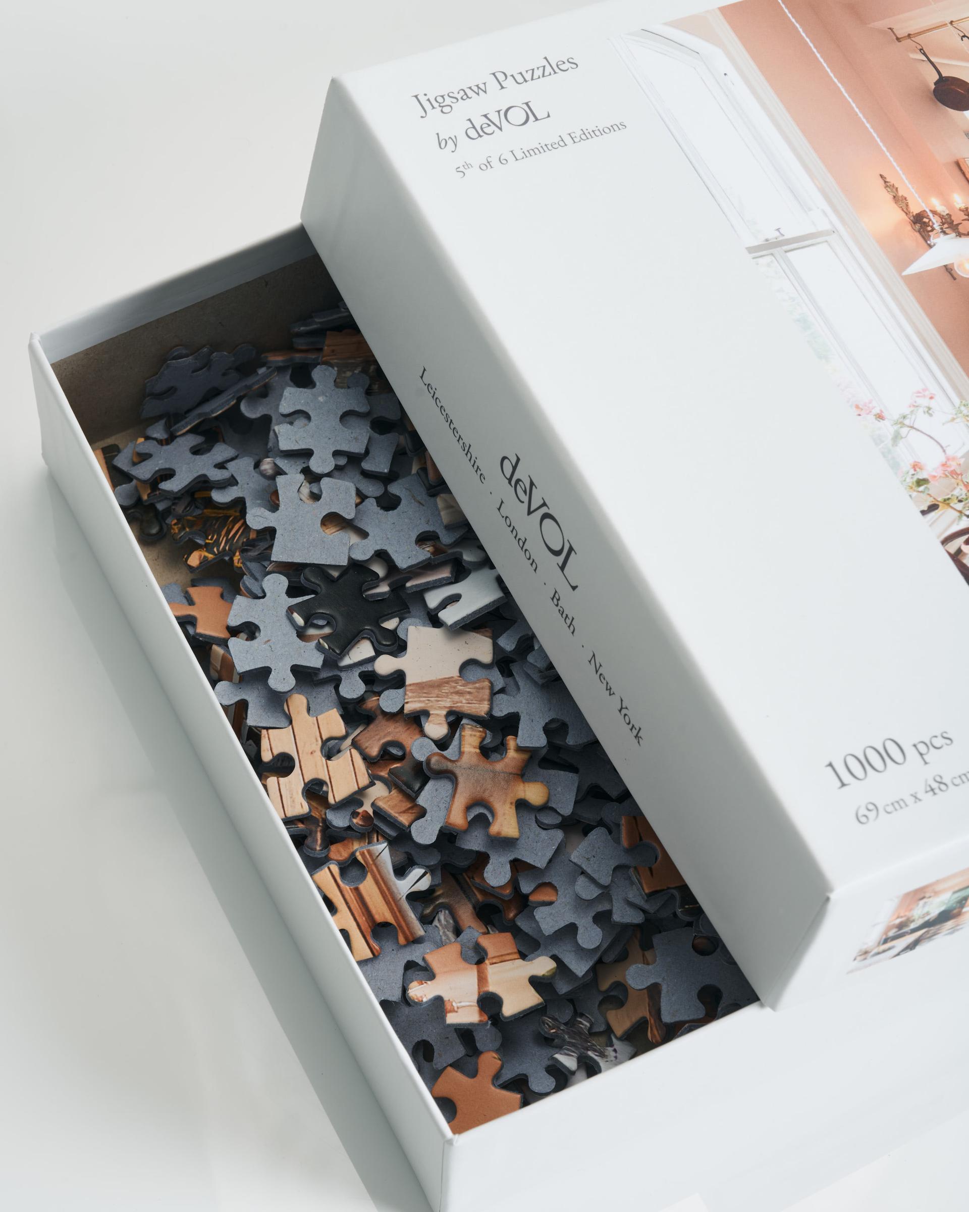 Looking into an open white jigsaw puzzle box, revealing unassembled pieces inside.