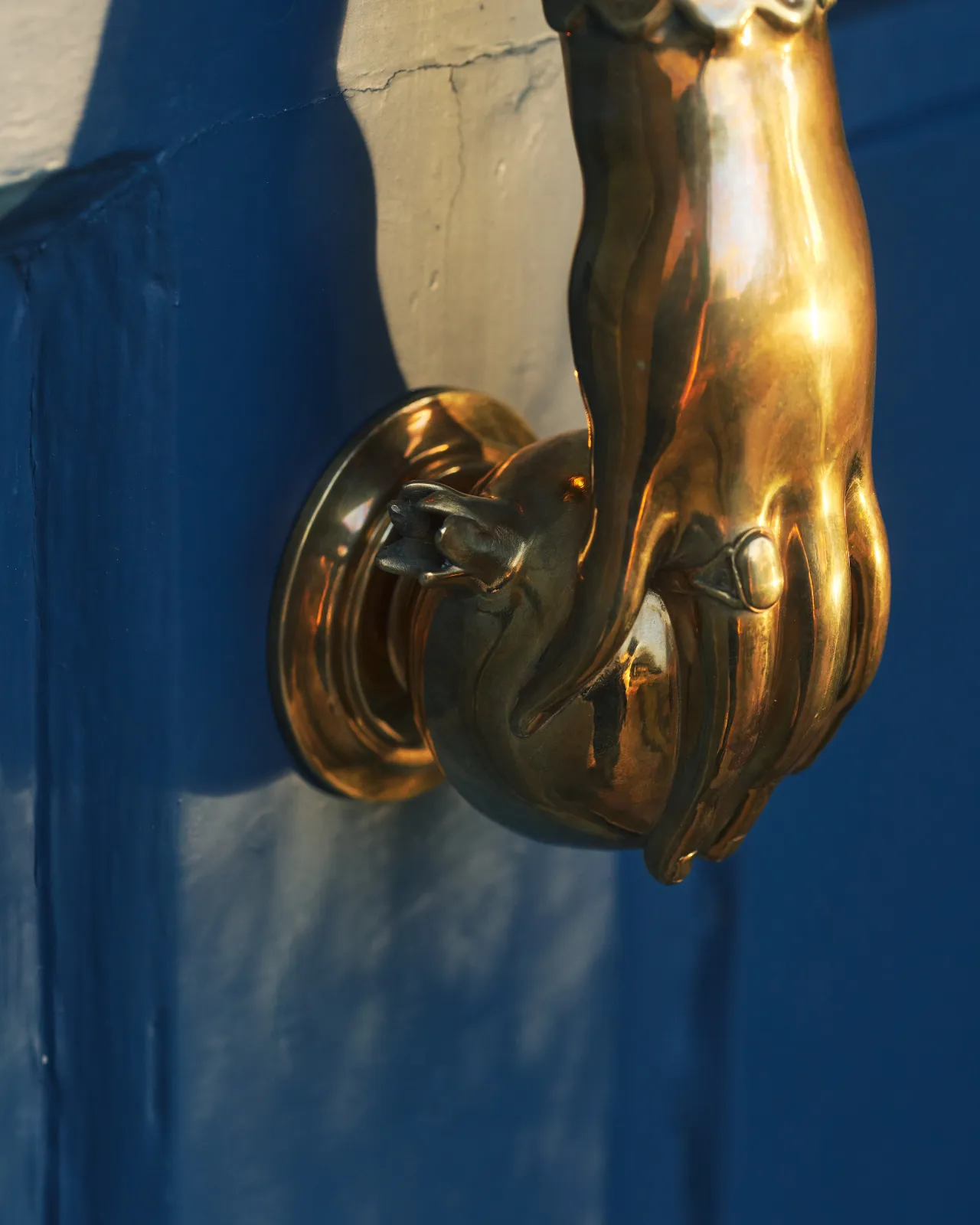 A close-up view showing the knocker part of a decorative brass door knocker, shaped like a pomegranate.