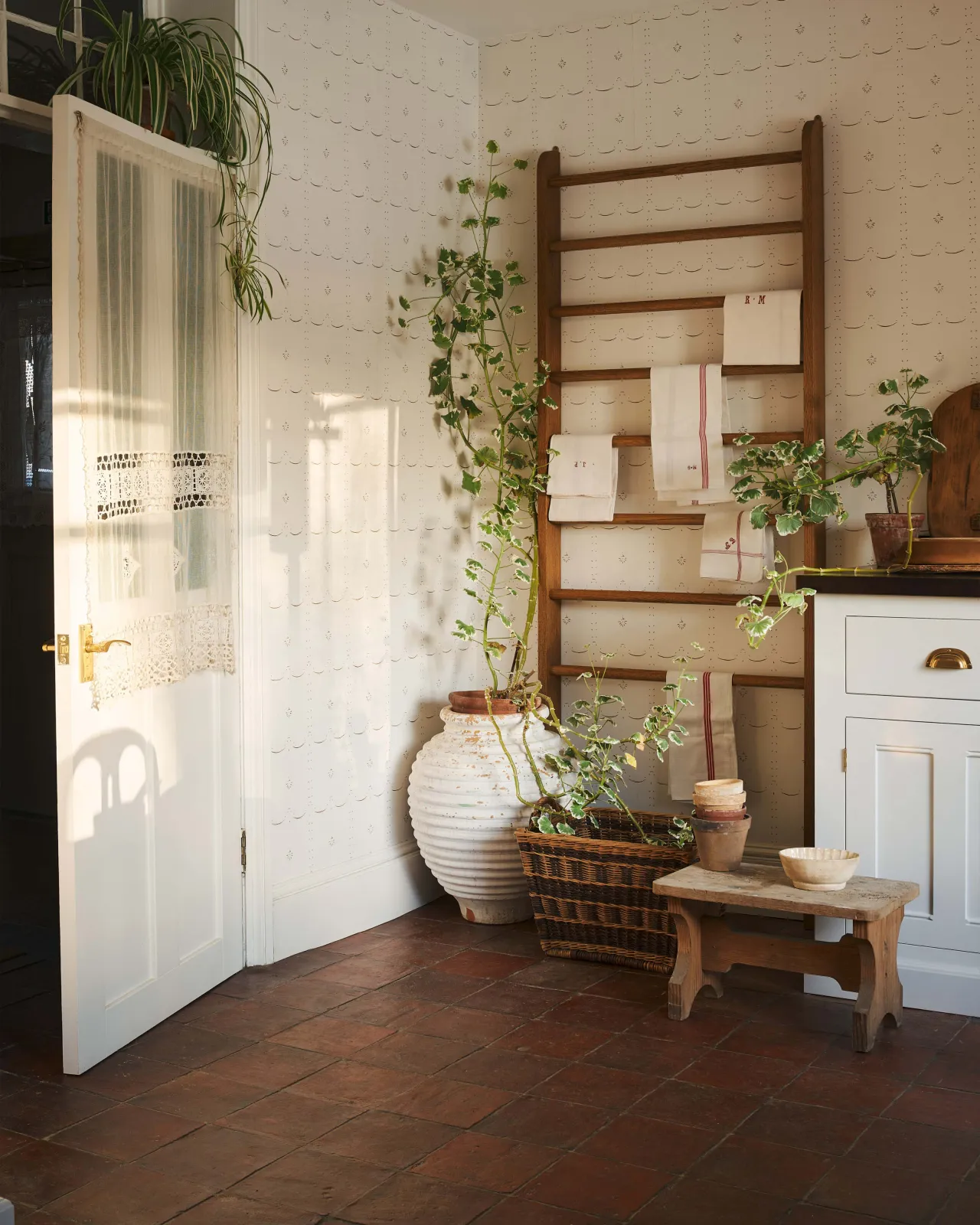 A classic English scullery room decorated with white, wooden accent and antiques that are warmed up with the Terracotta Square tile floor.