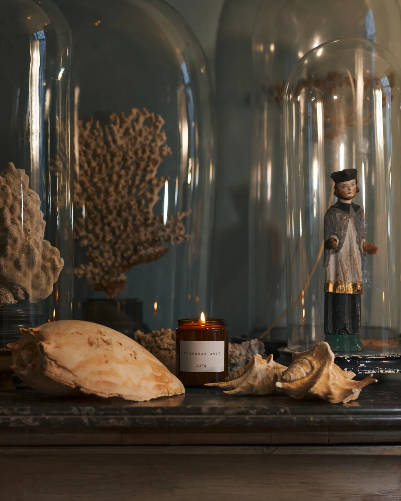 a front on shot of the medium candle surrounded by dried sea shells on a black stone top dresser.