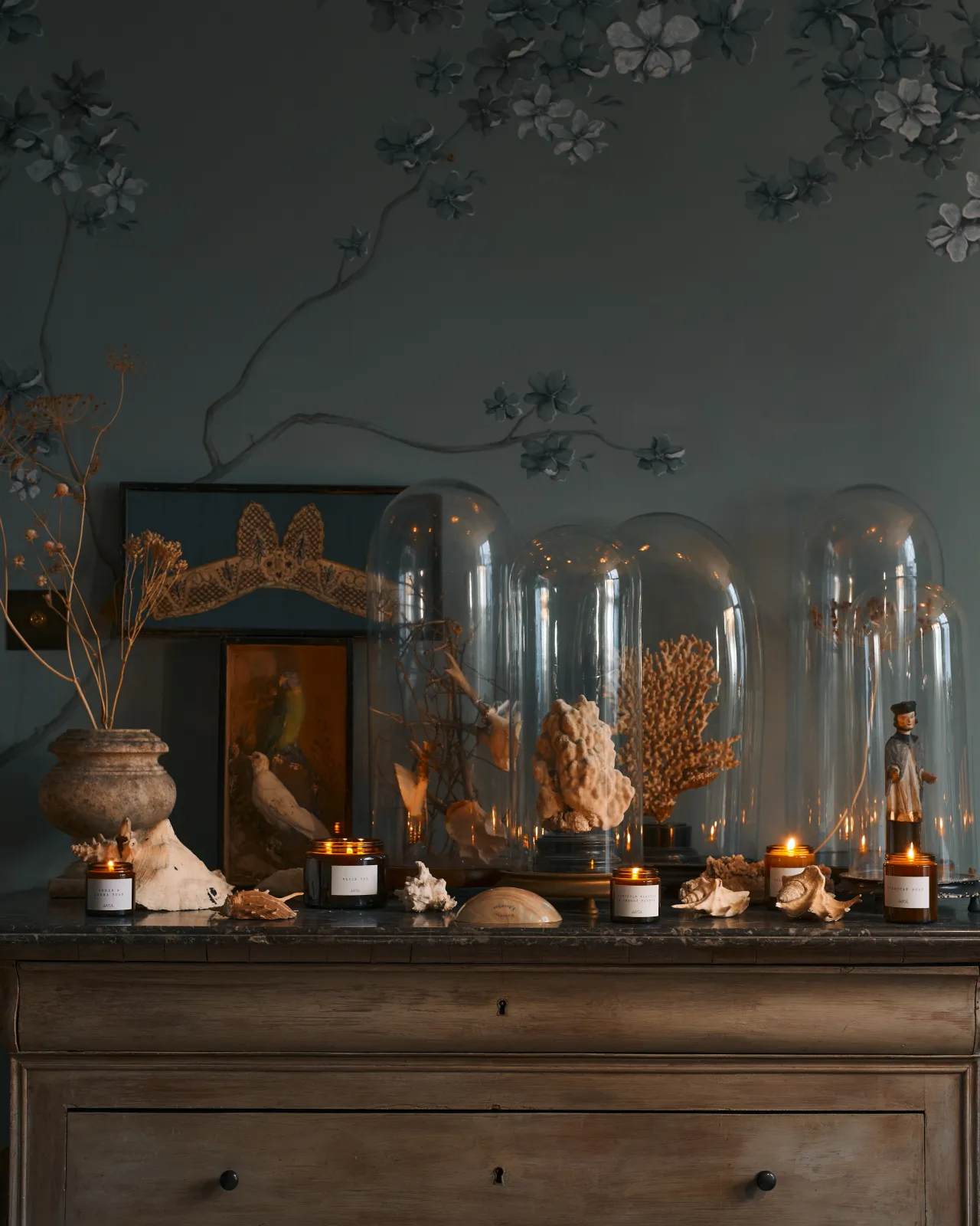 a front on shot of the medium candle surrounded by dried sea shells on a black stone top dresser.