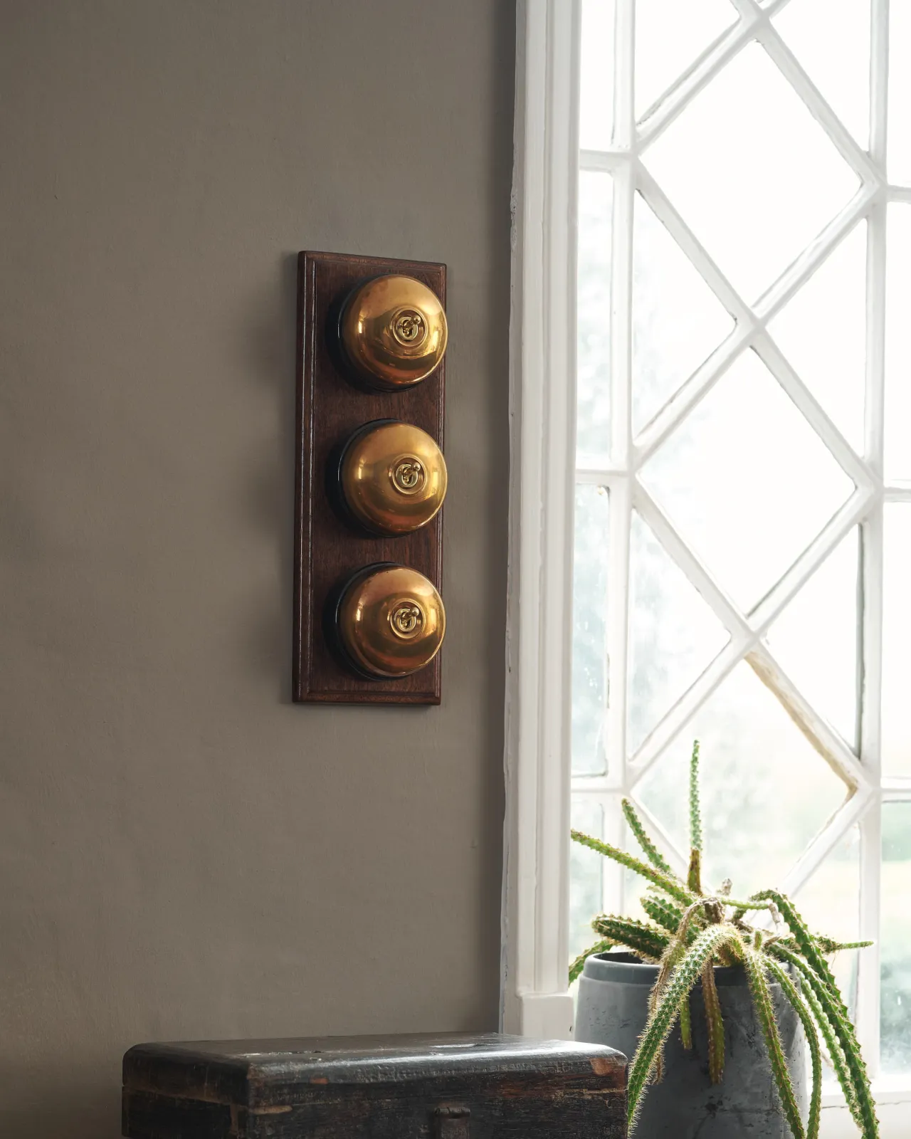 Three Heirloom Brass deVOL Dolly Toggle Switches fitted to a stained sapele pattress.