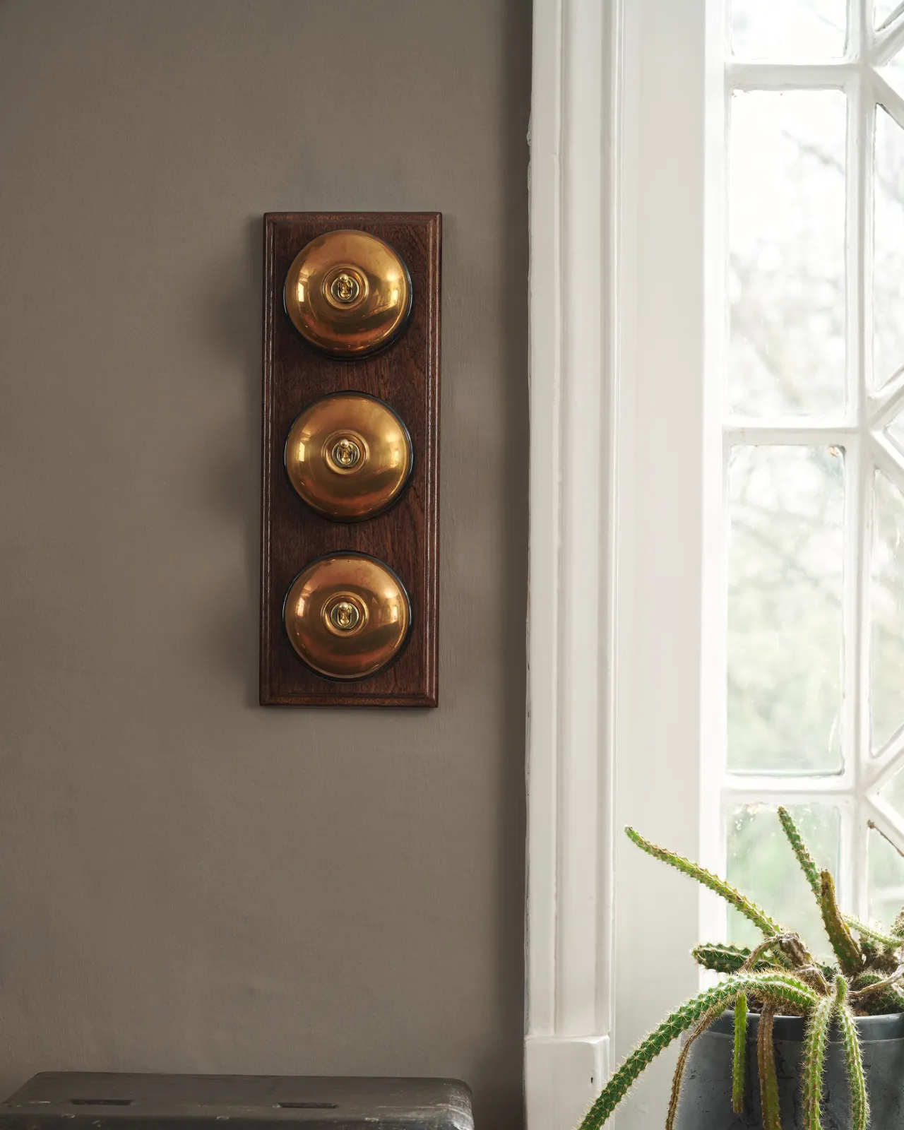 Three Heirloom Brass deVOL Dolly Toggle Switches fitted to a stained sapele pattress.