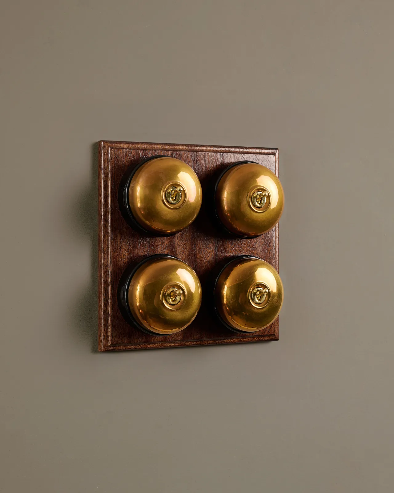A bank of four Heirloom Brass Dolly Toggle Switches fitted to a richly stained Sapele pattress. 