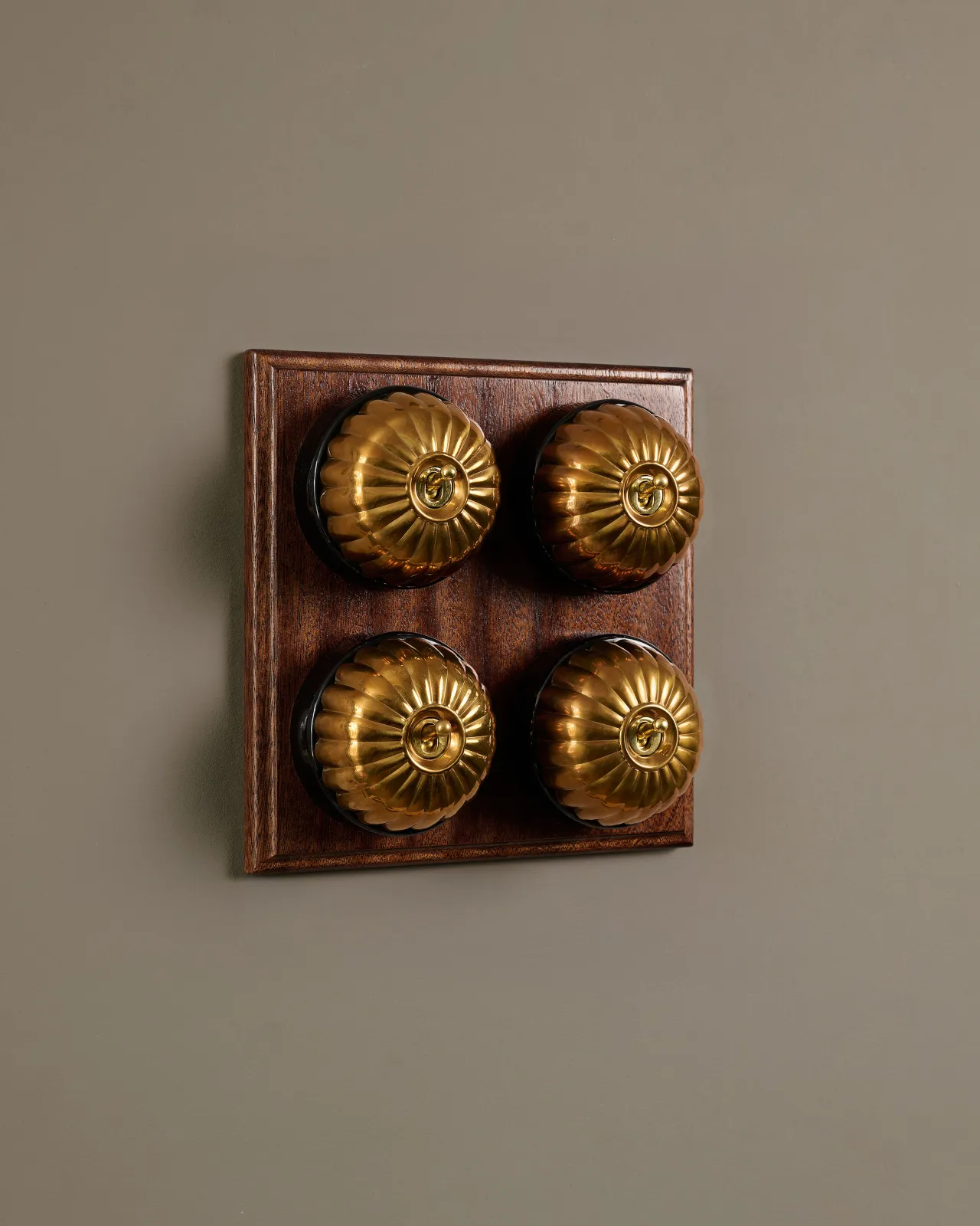 A bank of four Heirloom Brass Jelly Toggle Switches fitted to a Mahogany Finish pattress.