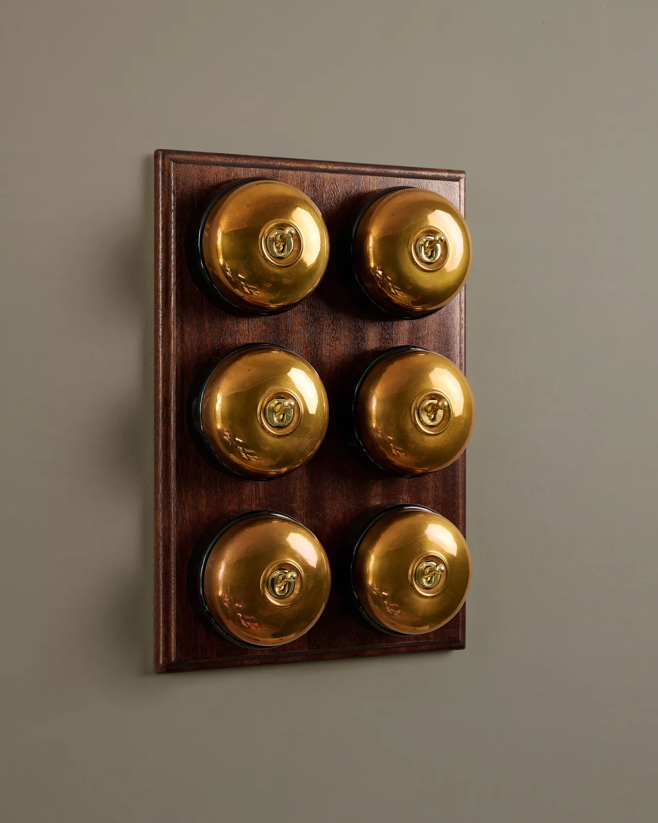A bank of six deVOL Heirloom Brass Dolly Toggle Switches fitted to a Mahogany Finish pattress.