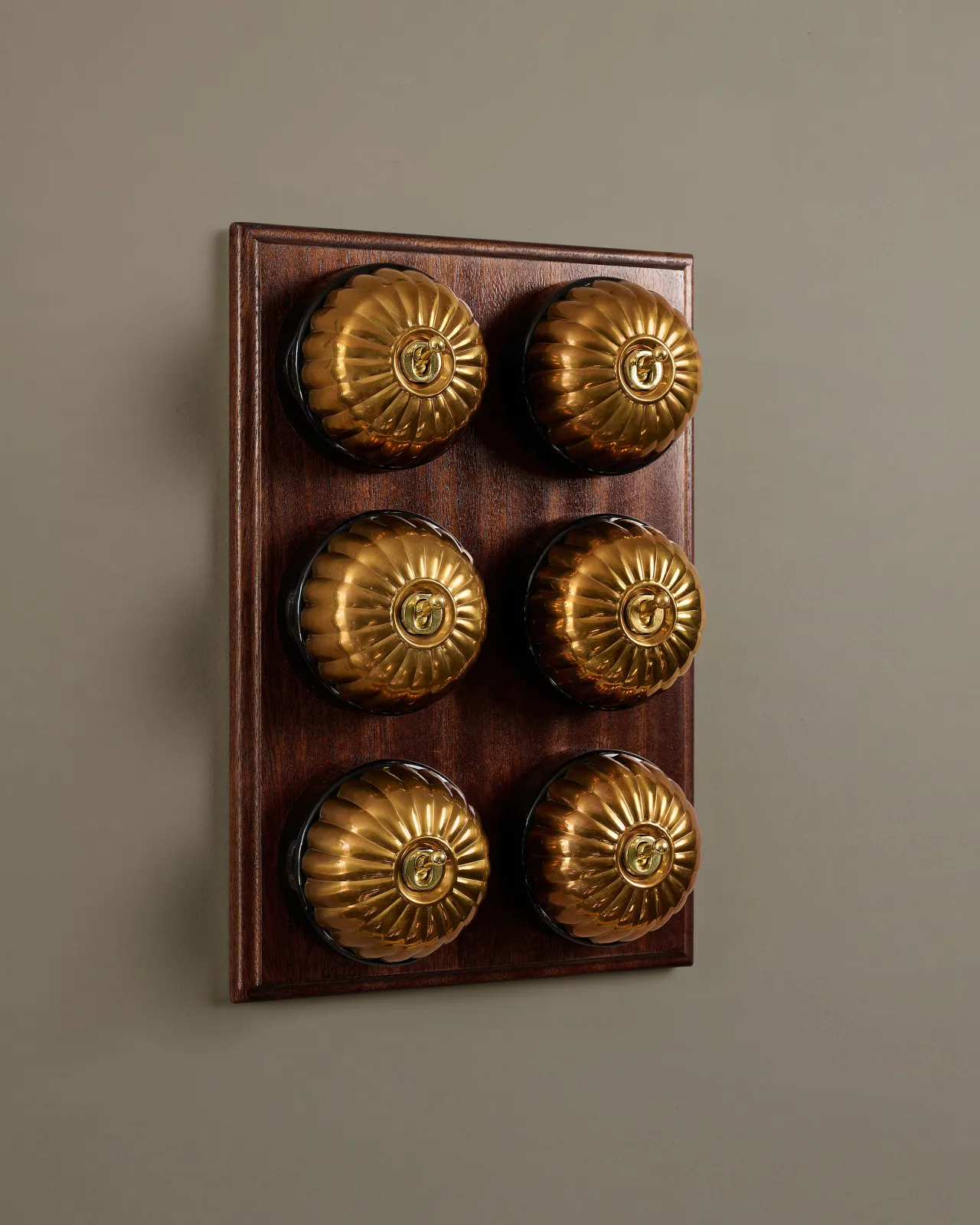 A bank of six deVOL Heirloom Brass Jelly Toggle Switches fitted to a Mahogany Finish pattress.
