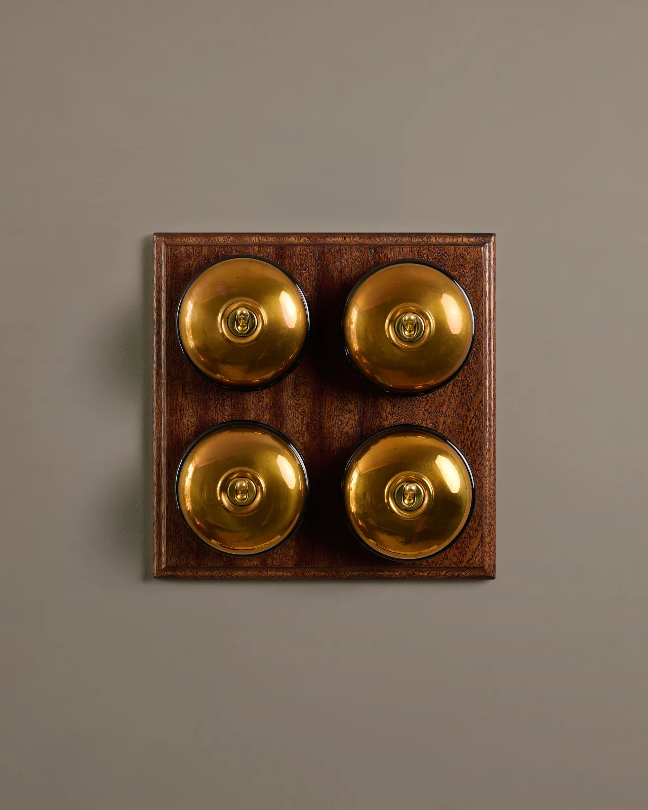 A bank of four Heirloom Brass Dolly Toggle Switches fitted to a richly stained Sapele pattress. 