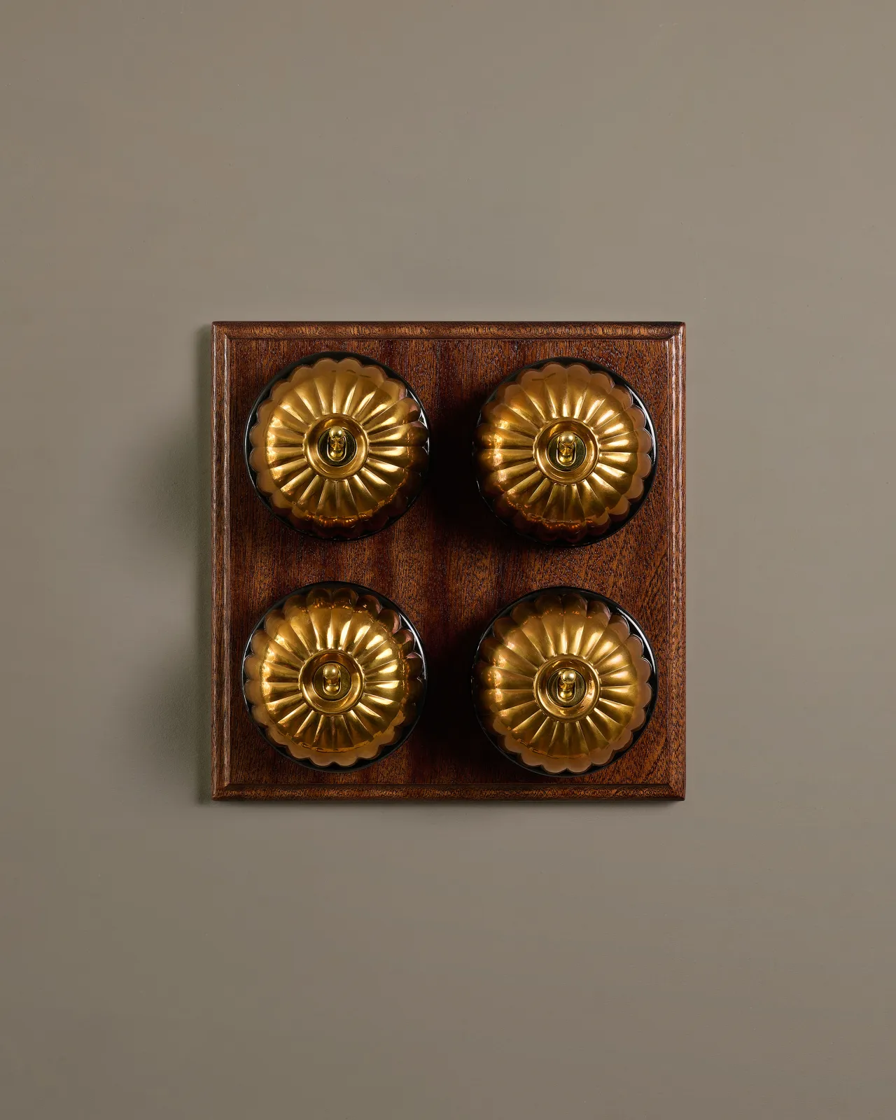 A bank of four Heirloom Brass Jelly Toggle Switches fitted to a Mahogany Finish pattress.