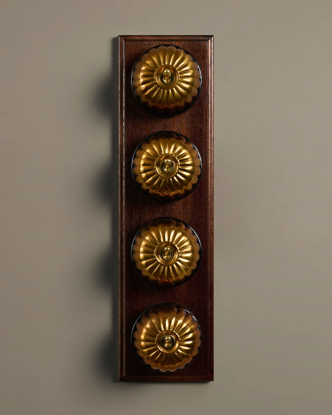 A row of four deVOL Heirloom Brass Jelly Toggle Switches fitted to a Mahogany Finish pattress.