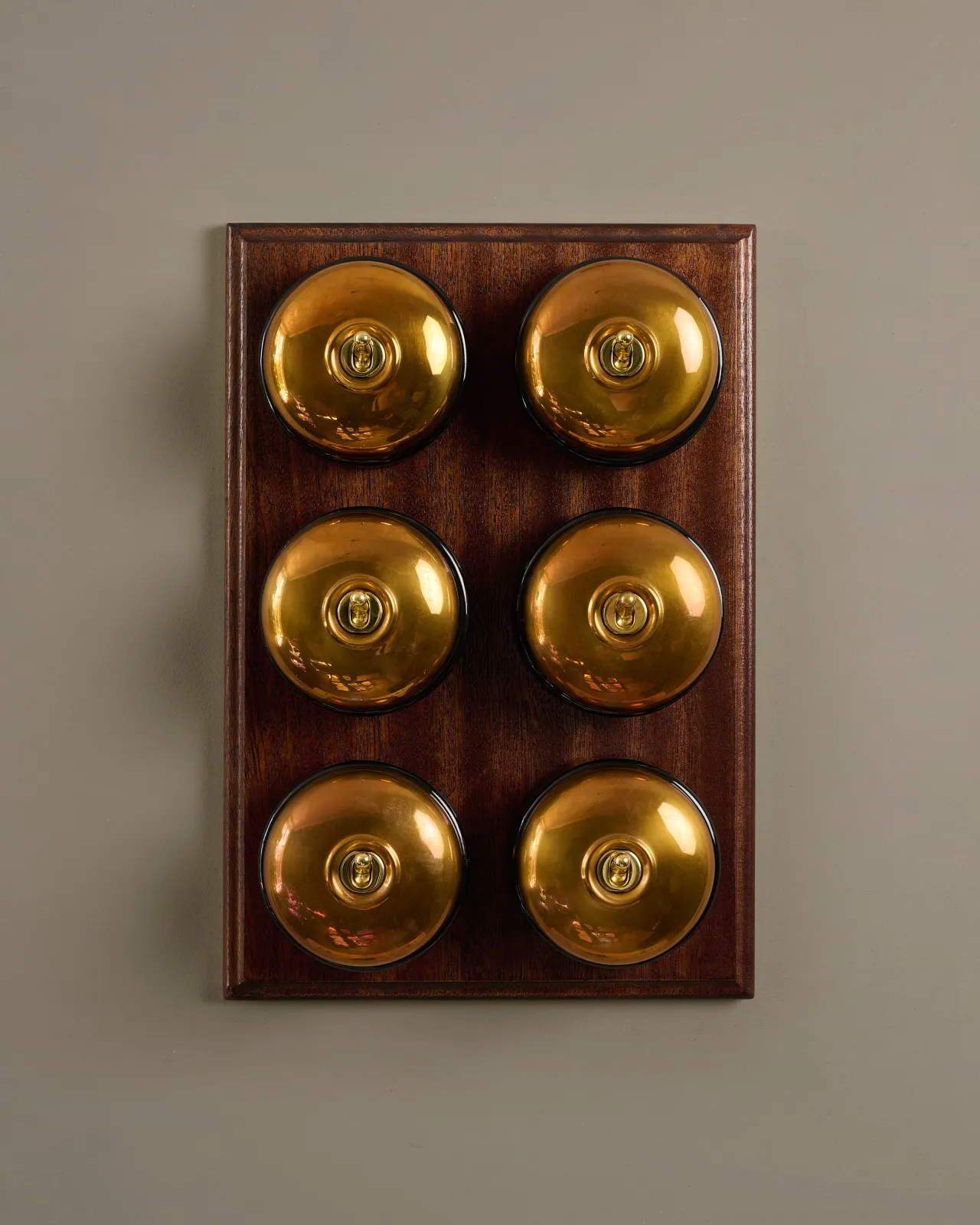 A bank of six deVOL Heirloom Brass Dolly Toggle Switches fitted to a Mahogany Finish pattress.