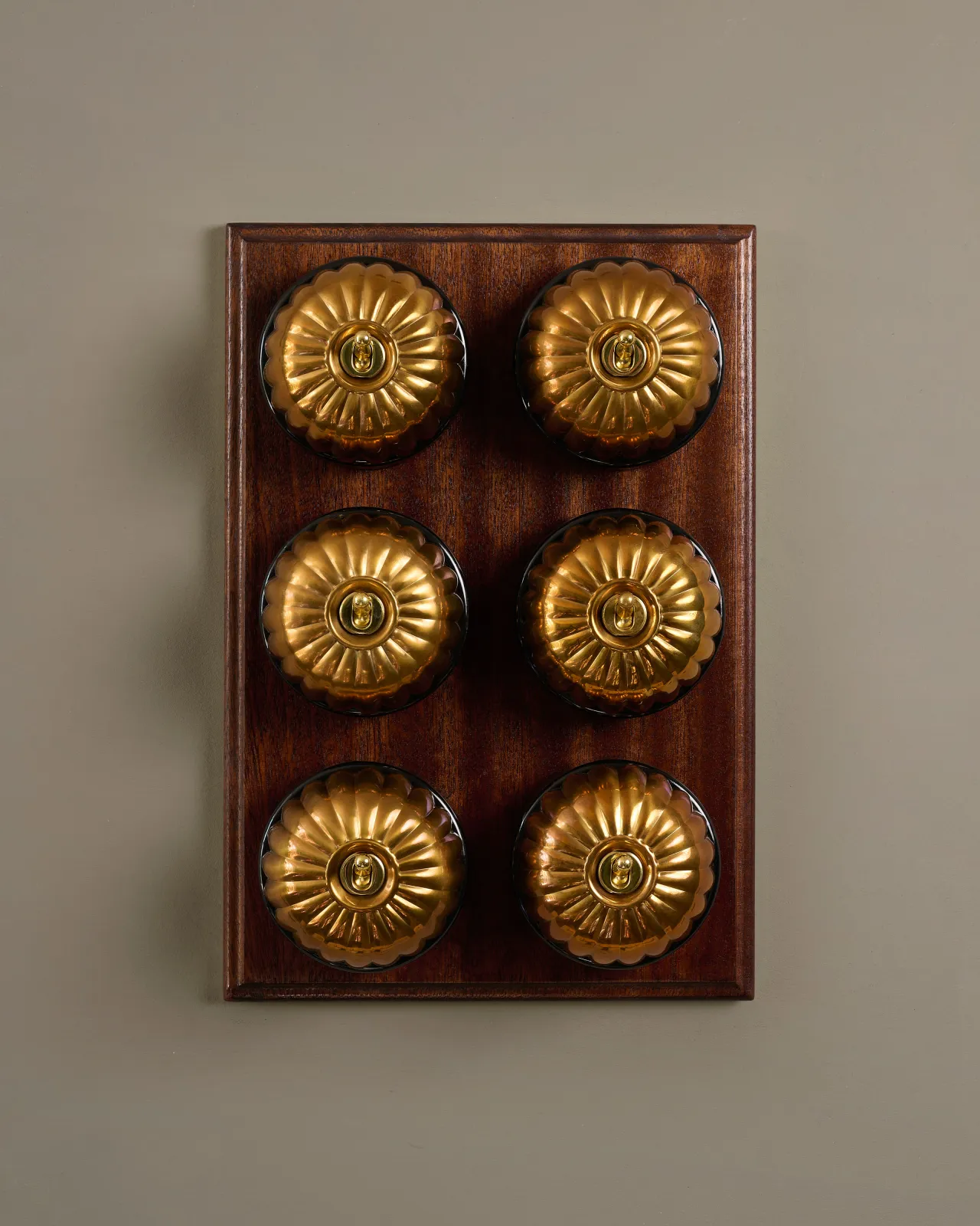A bank of six deVOL Heirloom Brass Jelly Toggle Switches fitted to a Mahogany Finish pattress.
