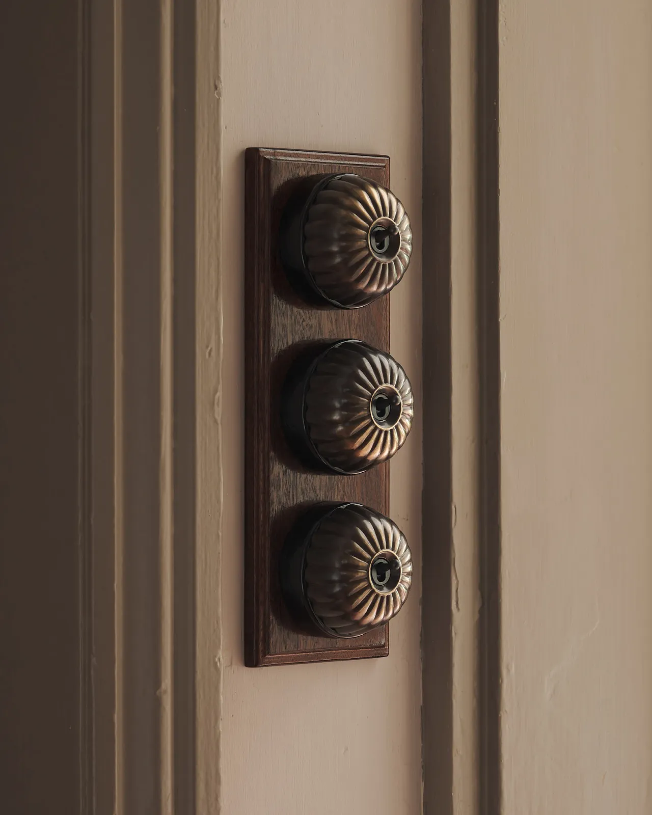 A set of three Jelly Toggle Switches finished in 'Oxidised Brass' and fitted to a richly stained Sapele pattress.