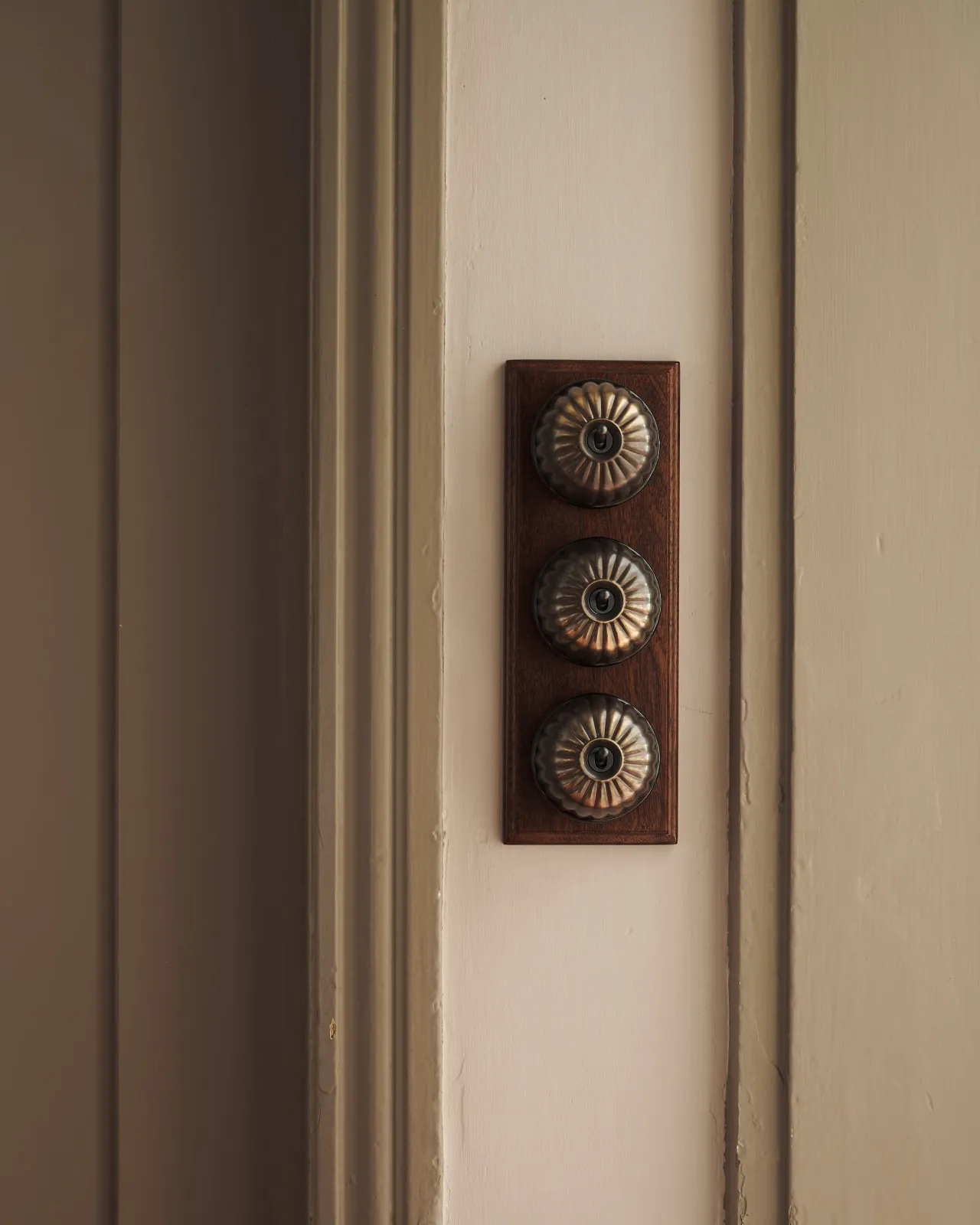 A set of three Jelly Toggle Switches finished in 'Oxidised Brass' and fitted to a richly stained Sapele pattress.