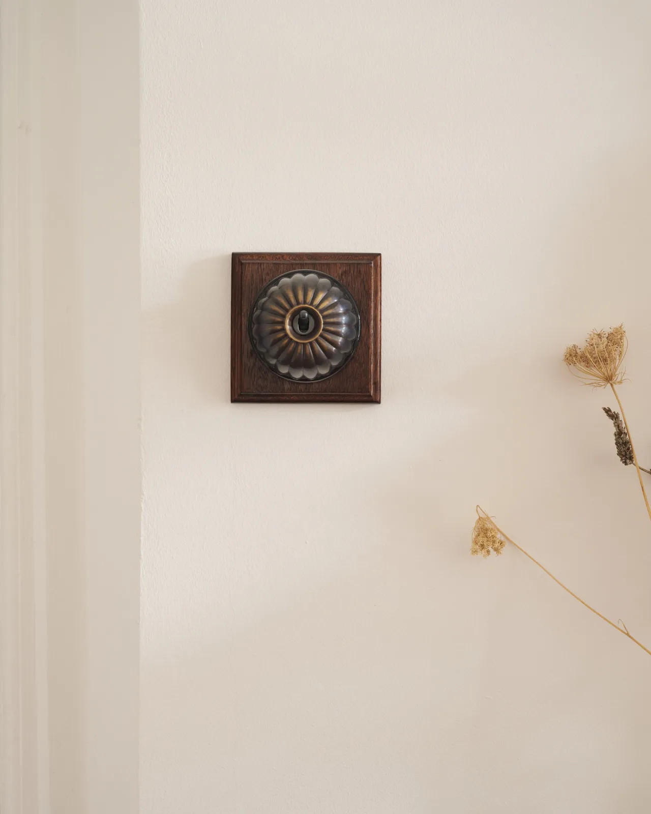 A deVOL Oxidised Brass Jelly Toggle Switch fitted to a Mahogany Finish pattress.