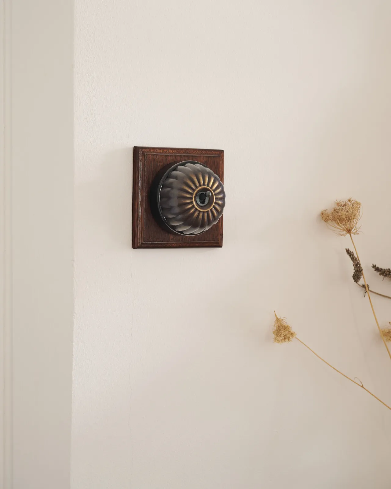 A deVOL Oxidised Brass Jelly Toggle Switch fitted to a Mahogany Finish pattress.