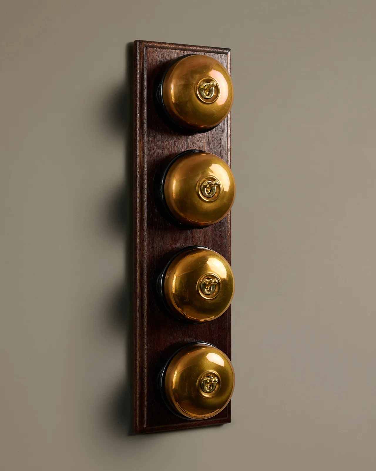 A row of four deVOL Heirloom Brass Dolly Toggle Switches fitted to a Mahogany Finish pattress.