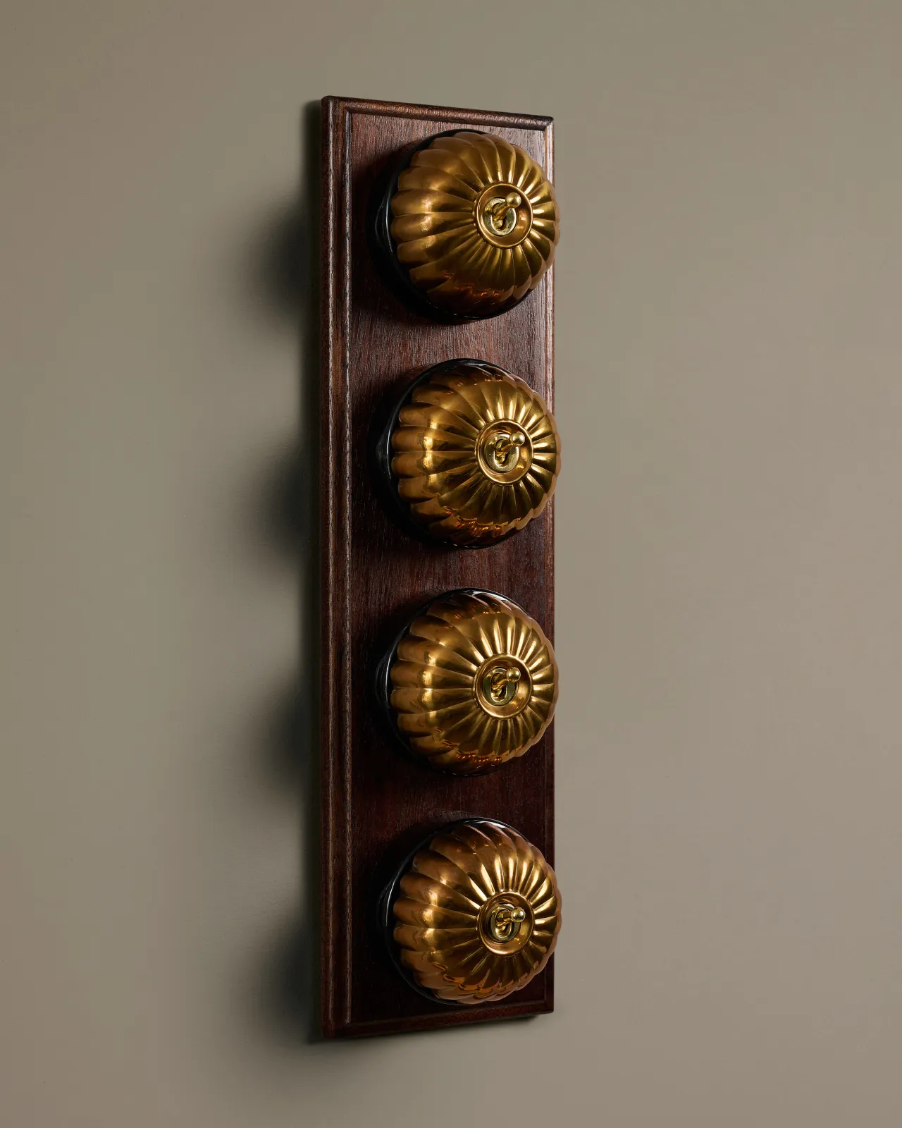 A row of four deVOL Heirloom Brass Jelly Toggle Switches fitted to a Mahogany Finish pattress.