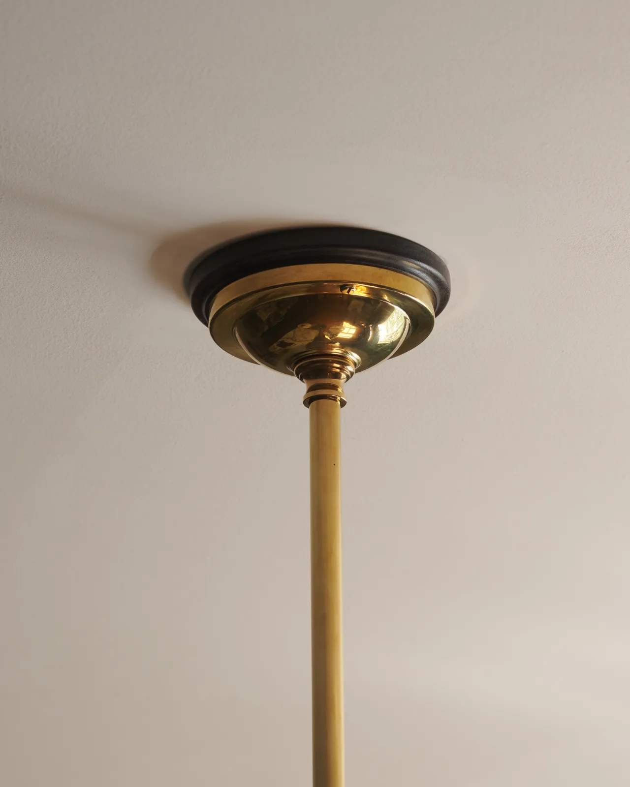 A traditional brass ceiling rose with a dark wooden pattress.