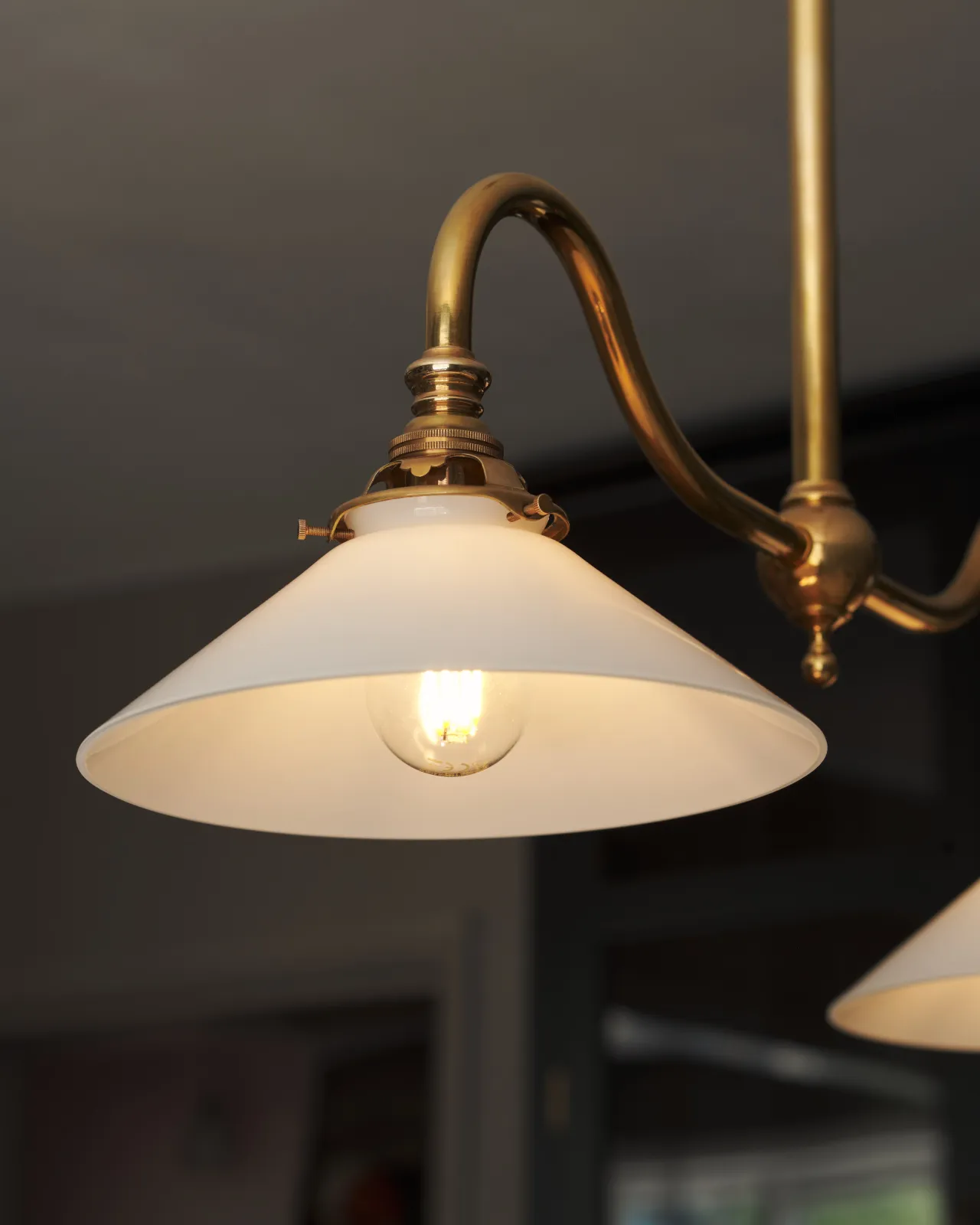 An illuminated small milk glass light shade seen from below, the light gives off a warm glow.