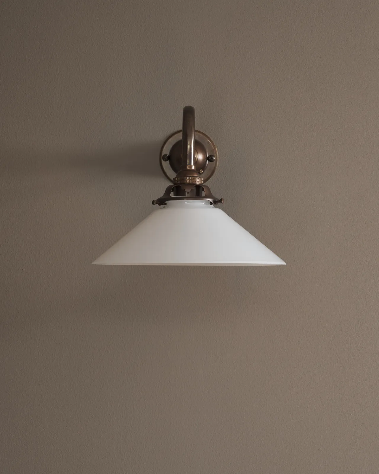 A close-up straight on view of a small milk glass wall light.
