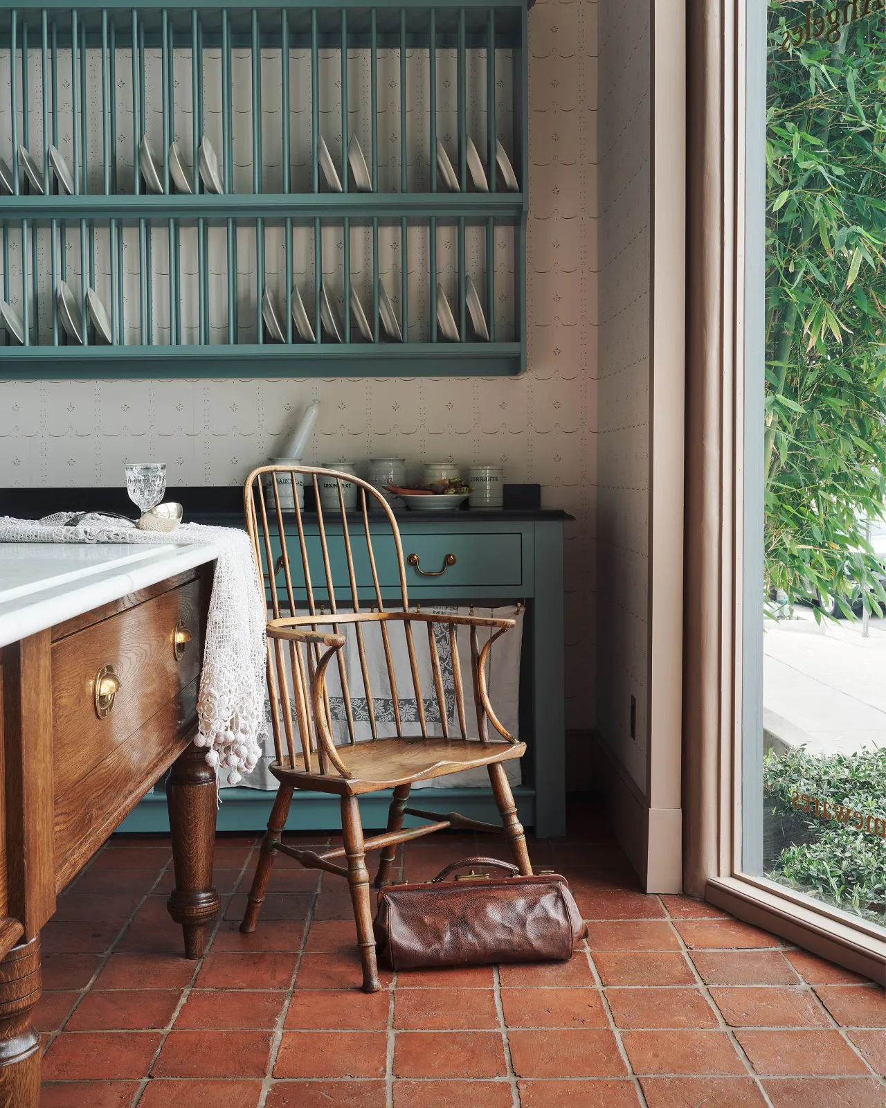 A terracotta tiled floor with a vintage Windsor chair and authentic Victorian-style freestanding English kitchen cabinetry.