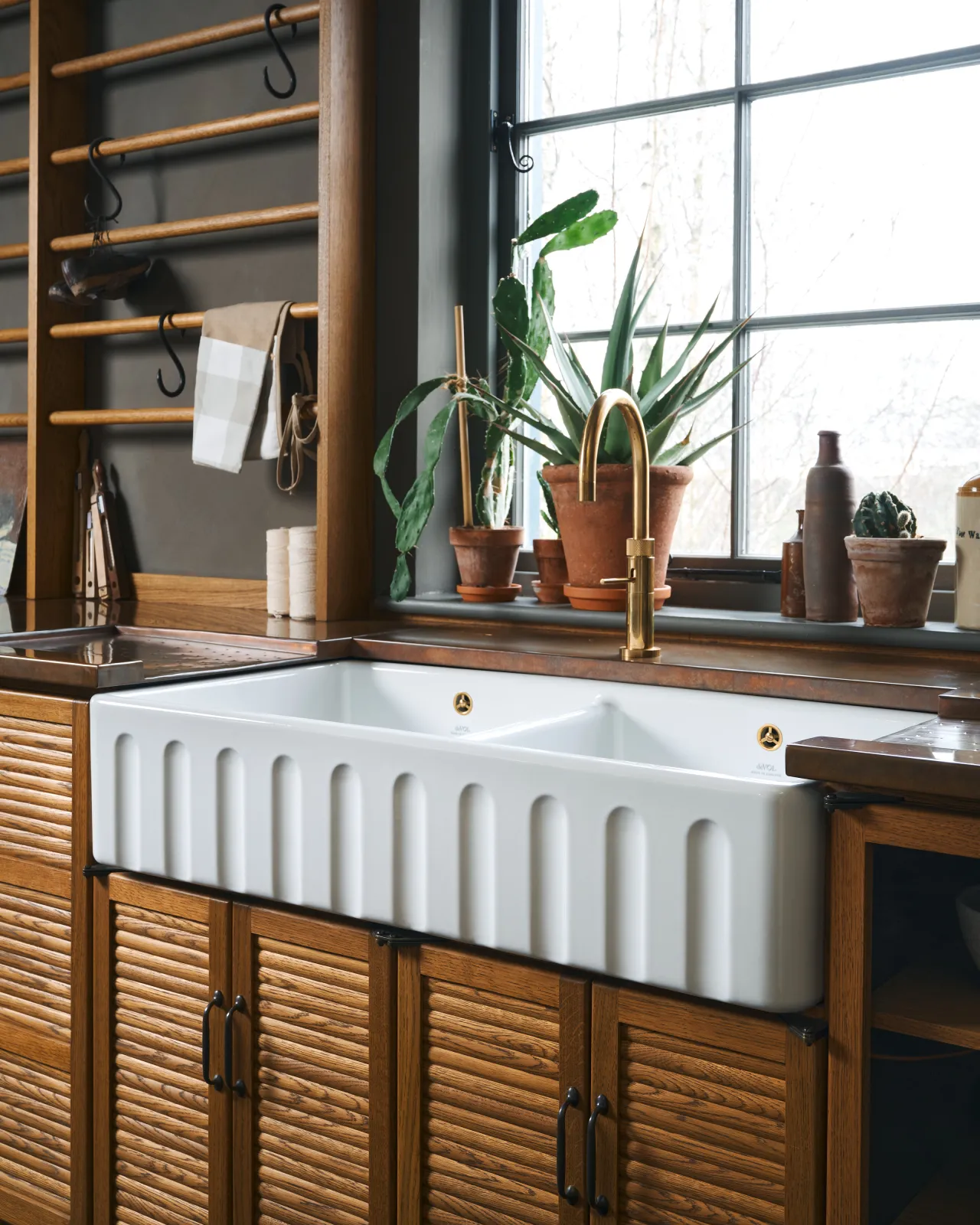 An oblique view of an extra large double bowl fluted ceramic Belfast sink in mid-century-style oak kitchen.