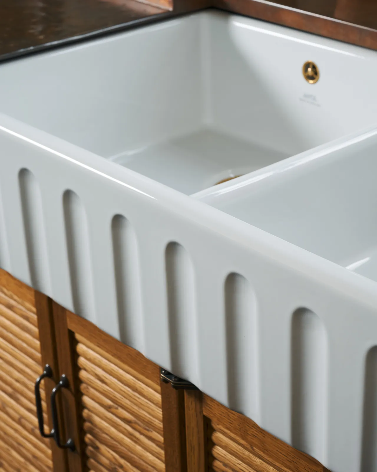 A close-up oblique view of the fluted front of an extra large double bowl ceramic Belfast sink.