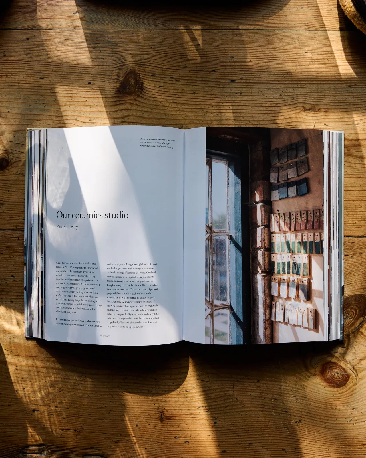 A hardback book open to a chapter titled 'Our ceramics studio' by Paul O'Leary. The photograph opposite shows a collection of ceramic glaze test tiles on display in a studio.