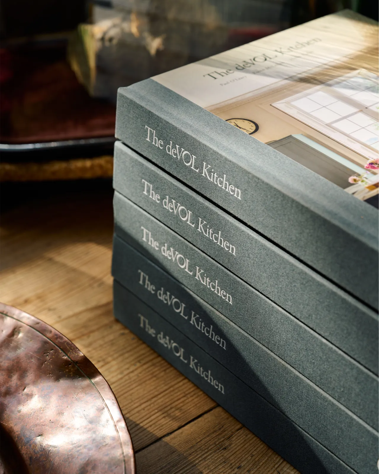 A stack of hardback books with blue fabric spines and the title embossed in traditional white lettering, 'The deVOL Kitchen'.