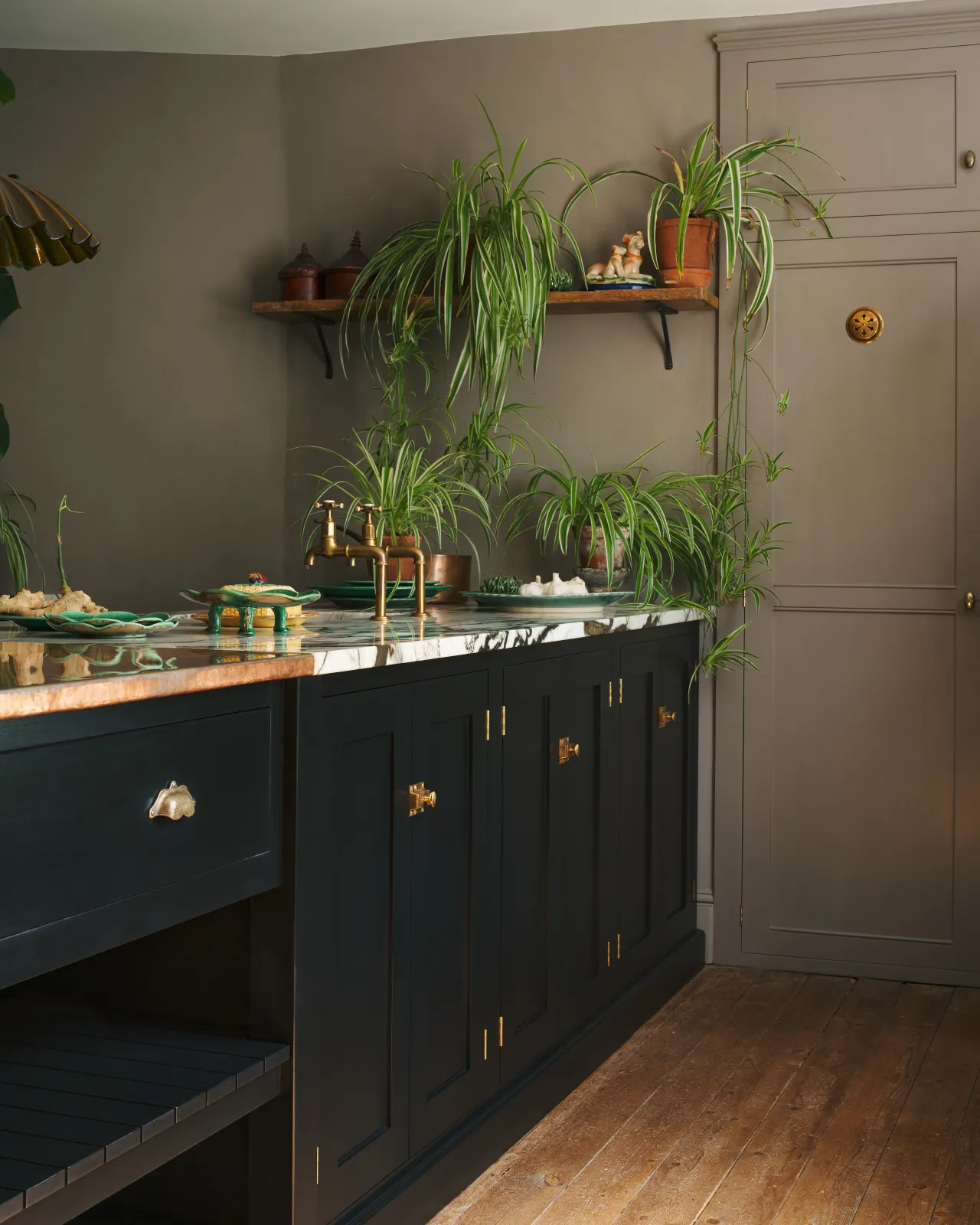 An oblique view of black painted kitchen cupboard doors with classic-style square cupboard catches in a warm burnished brass finish.