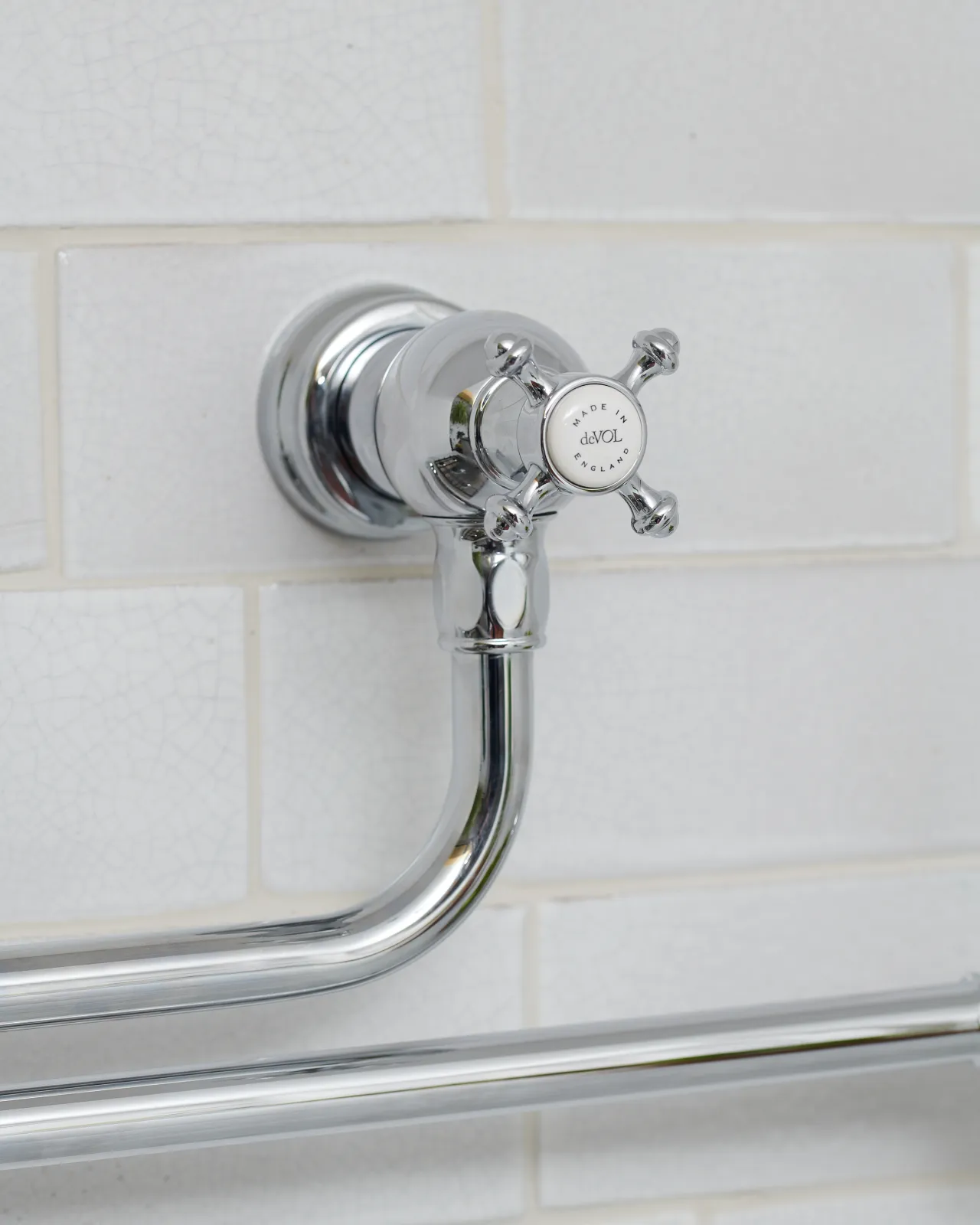 A close-up view of the crosshead handle at the base of a traditional-style chrome pot filler tap, a 'deVOL' logo can be seen in the centre of the handle.