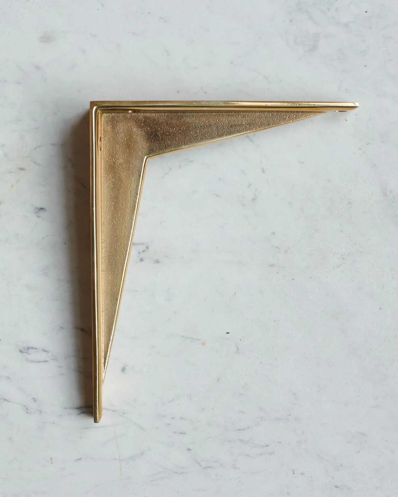 A side profile view of a classic brass utilitarian shelf bracket.