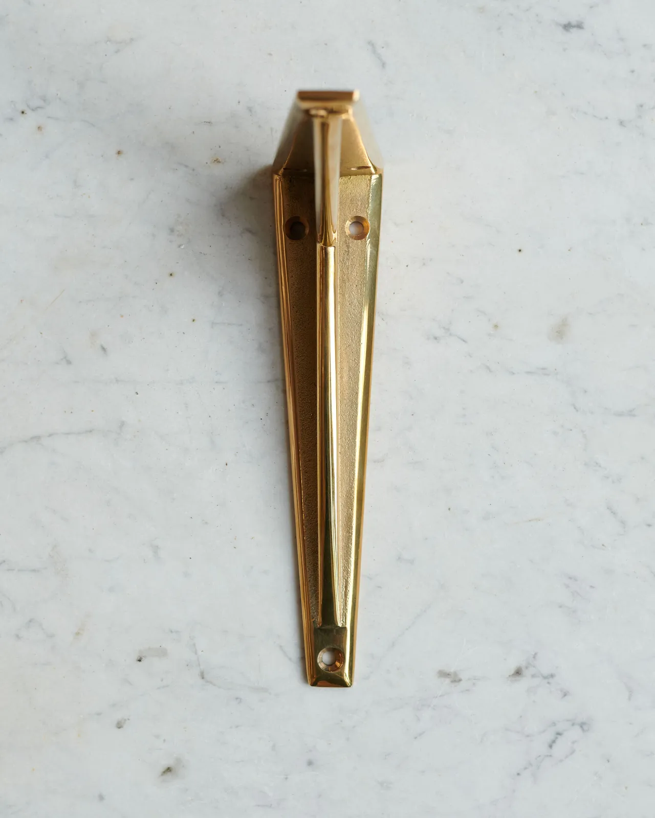 A front profile view of a classic brass utilitarian shelf bracket.