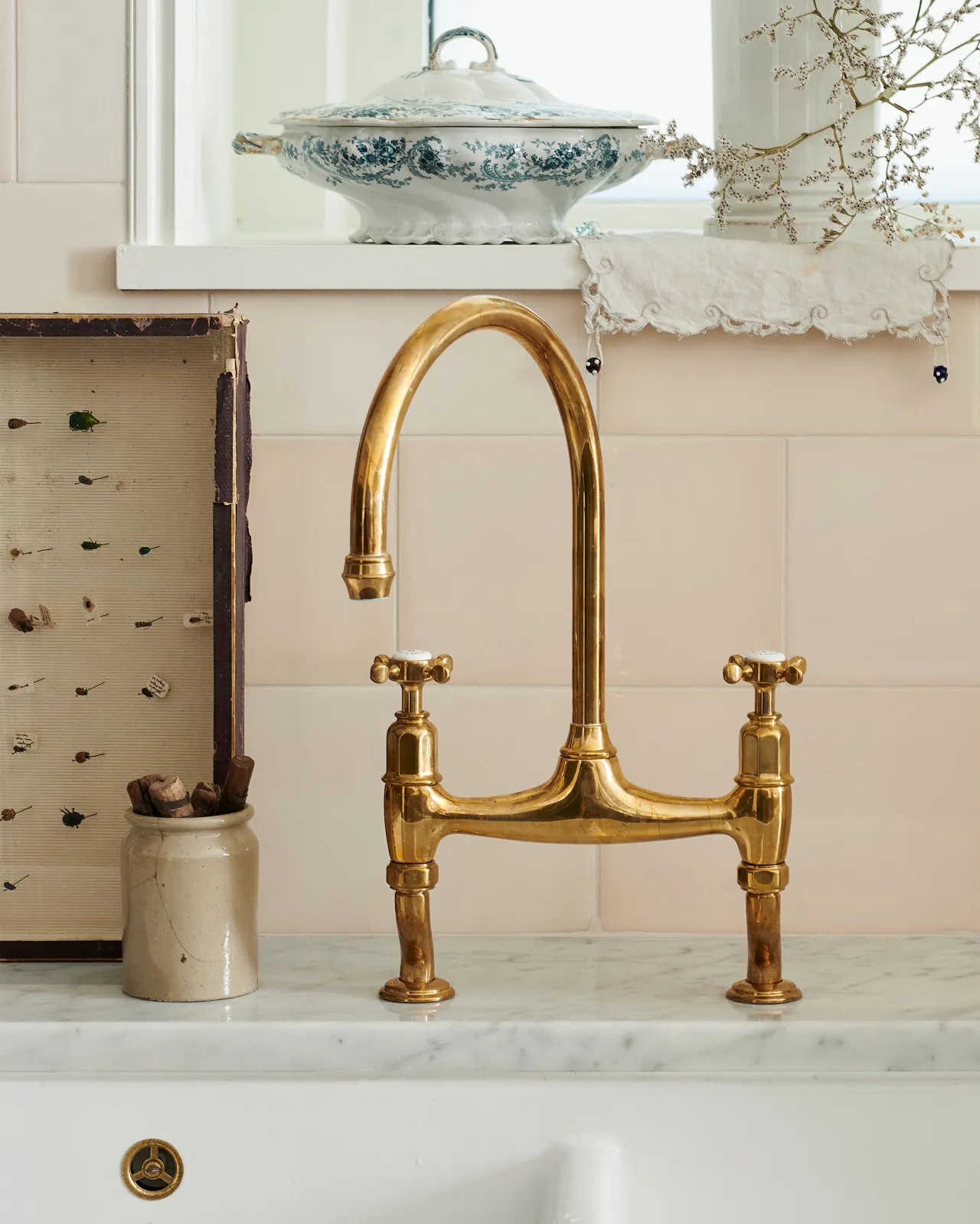 A straight-on view of a traditional-style aged brass mixer tap with crosshead handles.