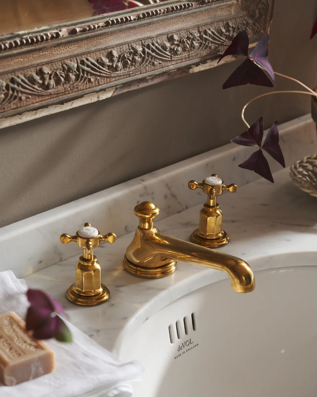 An oblique view of an aged brass mixer tap with crosshead handles for a bathroom basin sink.