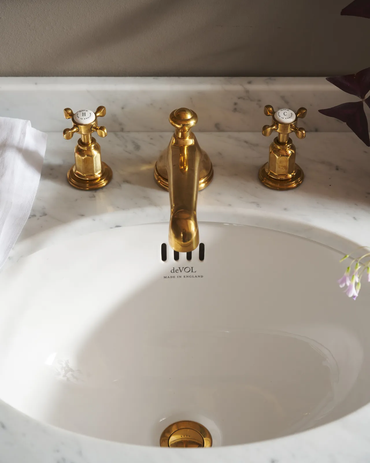 A front profile view of an aged brass mixer tap with crosshead handles for a bathroom basin sink.