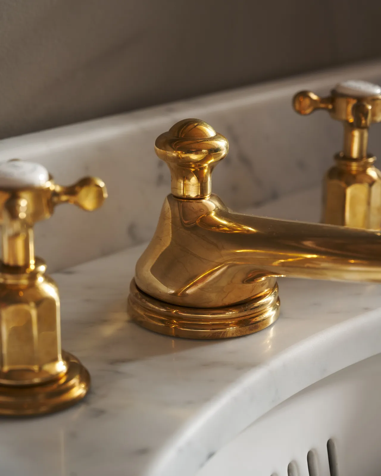 A close-up oblique view of an aged brass mixer tap with crosshead handles for a bathroom basin sink.